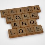Scrabble tiles arranged to spell 'Faith Hope and Love' on a white background, perfect for positivity themes.